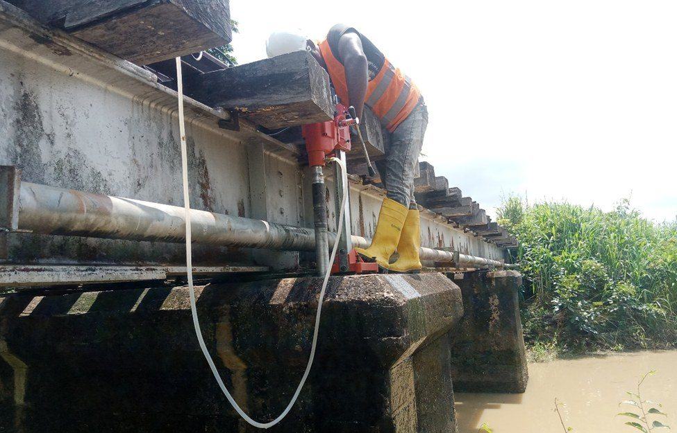 Engineer coring a bridge girder during a structural integrity assessment